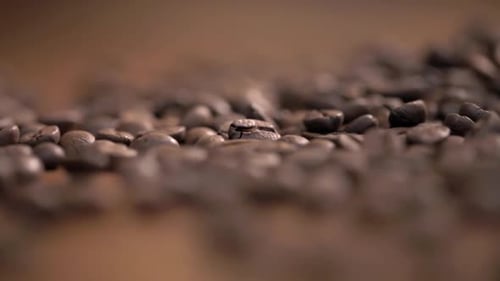 Scattering fresh coffee beans on a wooden table fly in different directions.