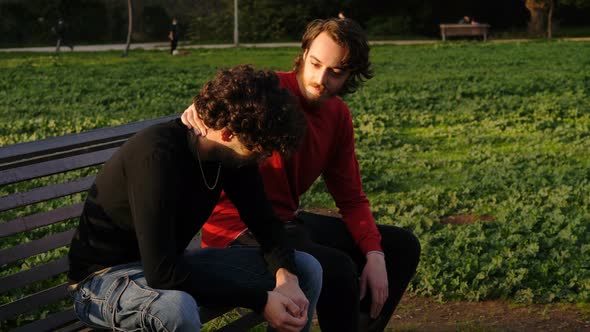 comfort, solidarity -man consoles his crying friend sitting on a park ...