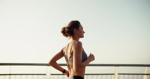 Happy Girl in a Sports Top on a Morning Run Young Fit Girl Running Against the Backdrop of Sunrise