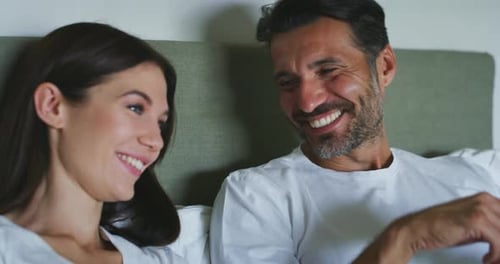 Authentische Aufnahme eines jungen, gerade verheirateten Paares, das einen Pyjama trägt, macht Spaß beim Sprechen und Lau