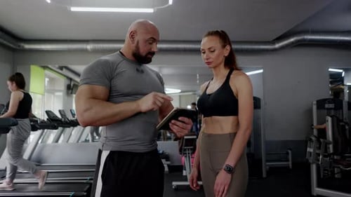 Trainer and Client Discussing Exercise Plan at Gym
