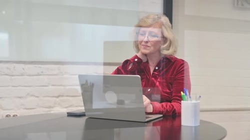 Mature Woman Working at Laptop Rubs Neck