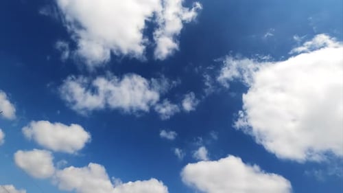 White cotton clouds floating fast in the sky. Blue summer sky with beautiful clouds. Time lapse.