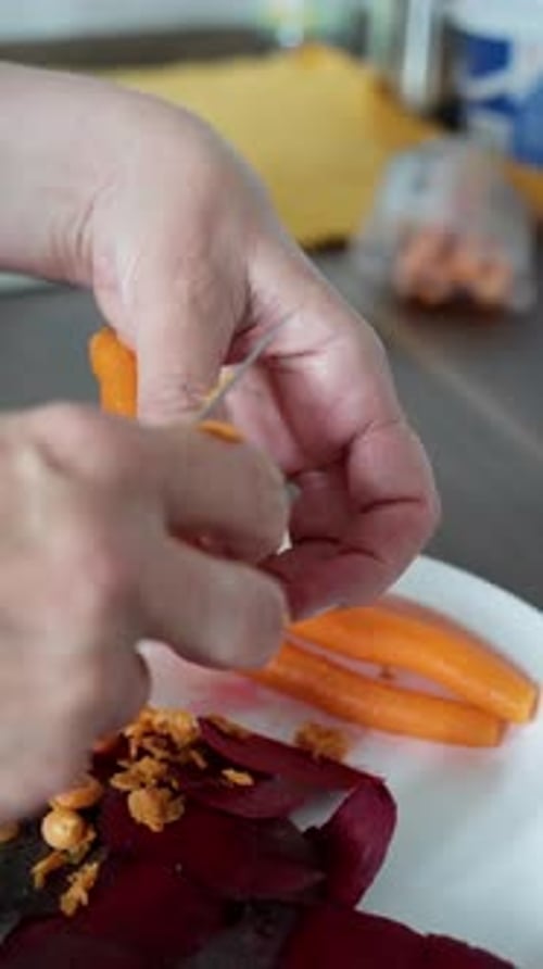 Hands Peeling a Carrot with a Knife