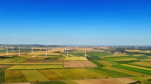 Multiple wind turbines installed in the vast fields. Green energy production. Aerial perspective.