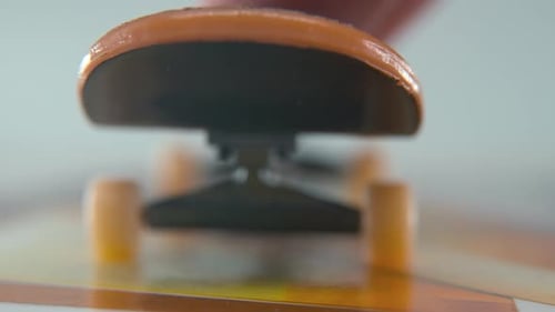 A close-up detailed shot of a mini skateboard, tiny white wheels, riding fingerboard, finger slide b