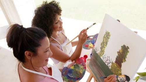 Painting on canvas together, women enjoying creative activity outdoors