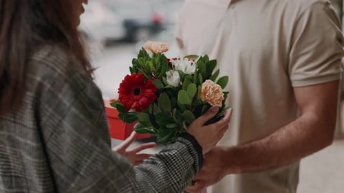 Man Gives Woman Flowers and Gift on City Street
