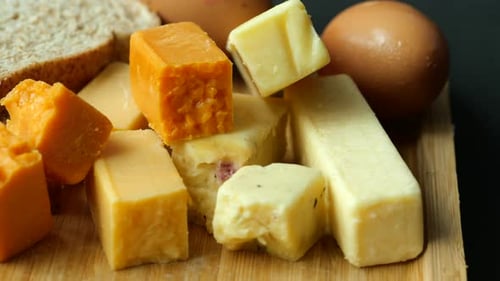 Cubitos de queso de color verde, amarillo y rojo sobre tabla de cortar