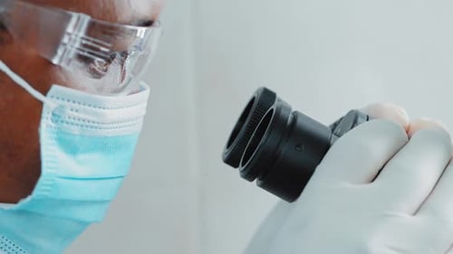 Ultra Macro Close Up Footage of a Male Scientist Wearing Medical Mask and Looking Into the