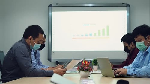 Four Professionals Analyzing Data in Masked Office Meeting