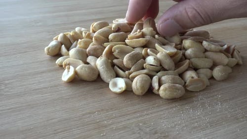 Hand Peacking Salted peanuts close up