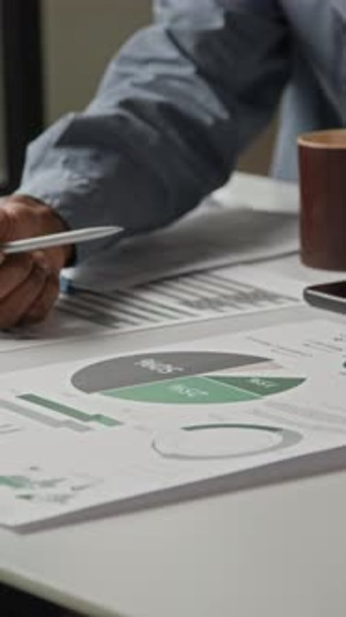 Two Colleagues Discussing Printed Chart at Office Desk