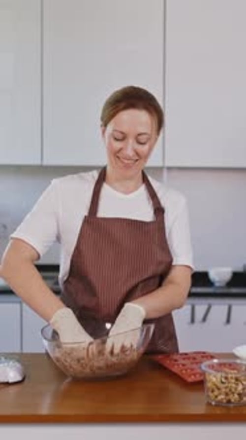 Woman mixing dough with gloves in kitchen