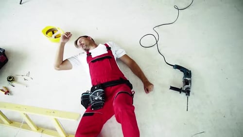 Injured construction worker lying on floor after accident at work top view slow motion