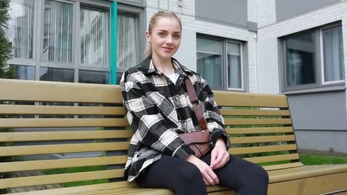 Young Woman Relaxing on Park Bench During Cloudy Autumn Day