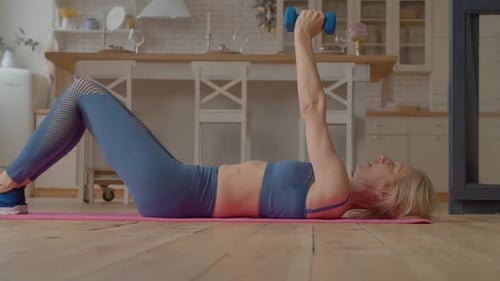 Blonde Woman Lifts Dumbbells at Home
