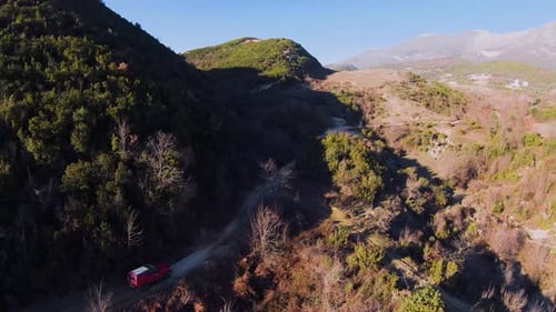 Areal shot of red rally car driving fast on dirt road fpv