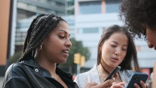 Stylish Friends Looking at Phones Together in City