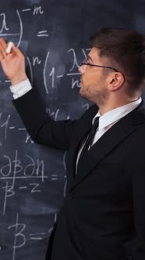 Man Teaching Math at Chalkboard in Classroom