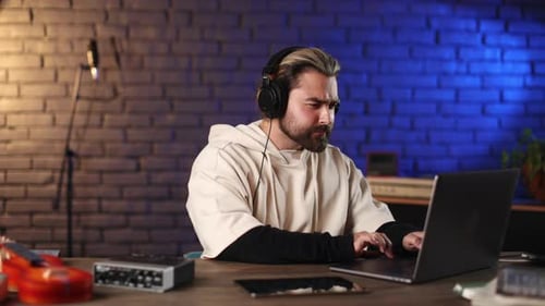 Talented Musician in Headphones Working on Laptop at Studio