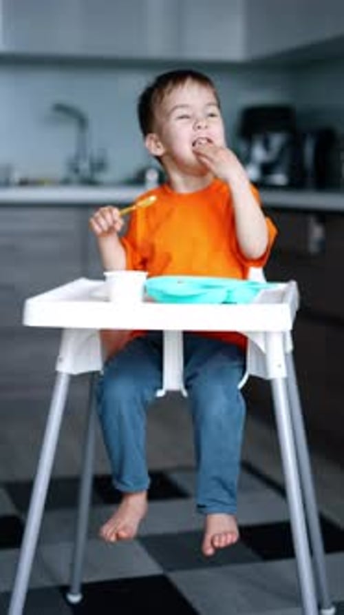 Happy Child Eating Snack in High Chair