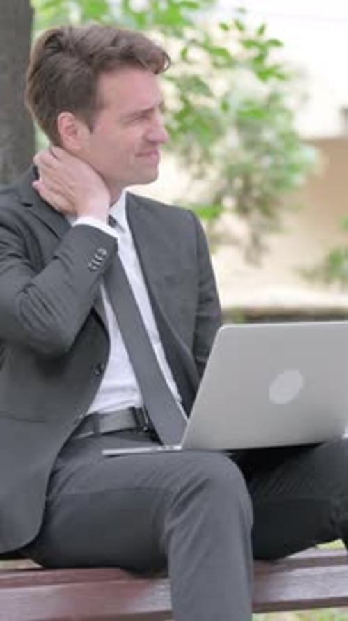 Man in Suit Using Laptop Outdoors on Bench