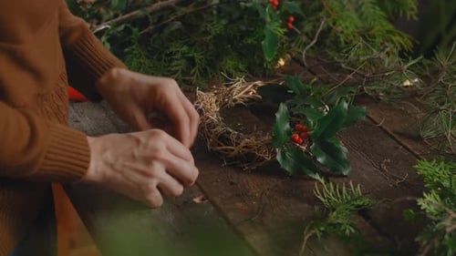 Female florist creating Christmas wreath in floral workshop.