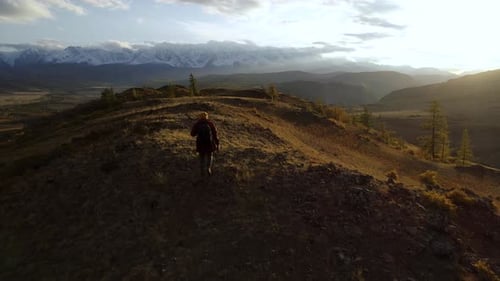 One Young Traveler Man Trekking and Hiking Alone on Ridge Path Back Shot