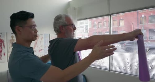 Physical Therapist Assists Man with Arm Exercises