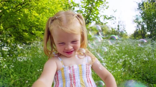 A Little Girl Concentrates on Bursting All the Soap Bubbles