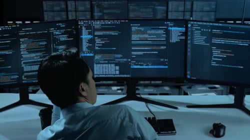 Back View Of Bored Asian Man Write Code With Multiple Computer Screens In office