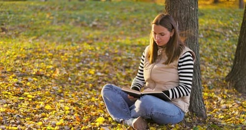 Woman Reading Book in Autumn Park