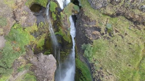 drone fly close to a natural waterfall with stone arch and green lush over the rock, fresh natural c
