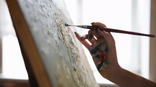 Close up view of woman's hand drawing picture by using brush