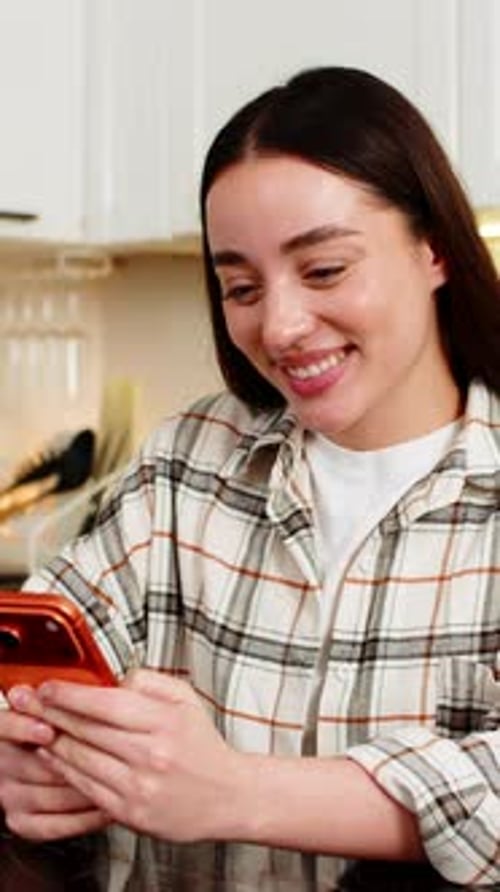 Smiling Woman Using Cellphone in Kitchen