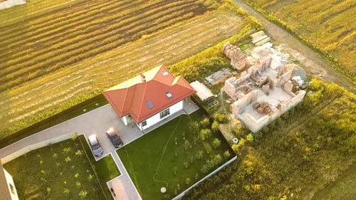 Top Down Aerial View of Two Private Houses One Under Construction with Wooden Roofing Frame and