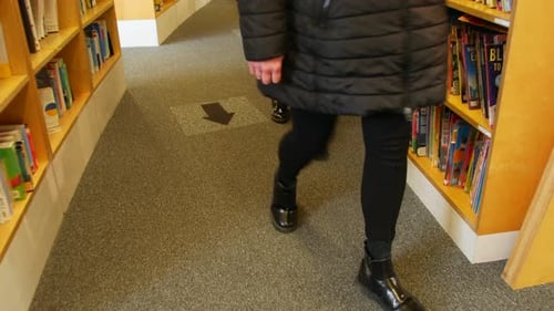 People walking through a library following the arrows on the floor