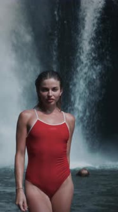 Woman Posing on a Waterfall Girl Stands on Island of Bali Female in Red Swimsuit Touches Wet Hair