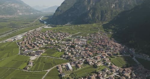 Aerial view of town surrounded by mountains and vineyards, Italy.