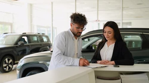 Car Saleswoman Giving Keys to Middle Eastern Customer in Dealership