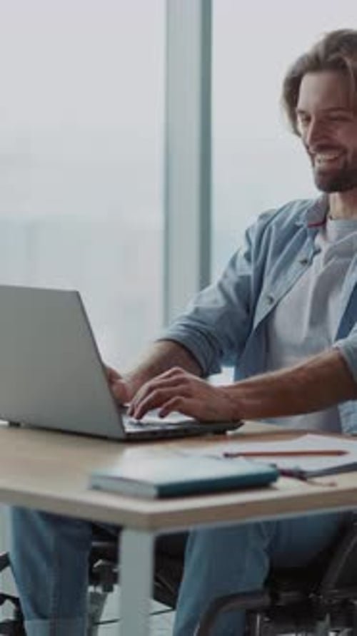 Man in Wheelchair Using Laptop at Desk