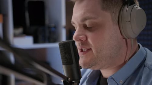 Close Up Radio Host Sit in Studio and Communicates with Audience Man in Blue Shirt and Headphones