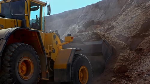 Yellow Wheel Loader Digging And Loading Up Soil. - Slow Motion