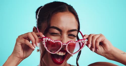 Fille, visage et clin d'œil avec des lunettes de soleil en studio pour flirter, Saint-Valentin et personnalité amusante