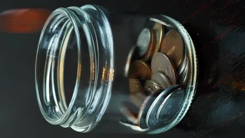Person throwing coins into glass bottle, close up