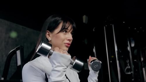 Woman Exercising with Dumbbell in Modern Gym Female Athlete Lifting Weights with Focus