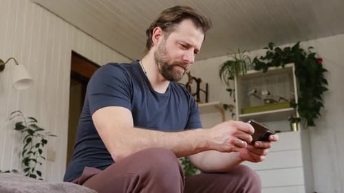 Adult Man Uses Smartphone at Home