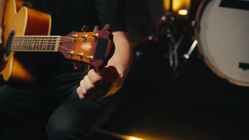 Young Musican Man Checking Strings of Acoustic Guitar Closeup Male Guitarist Tuning Sound of Musical