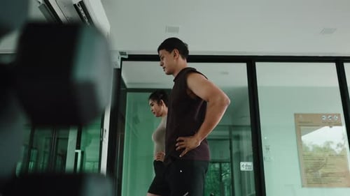 Athletic Couple Running on Treadmills During Gym Workout